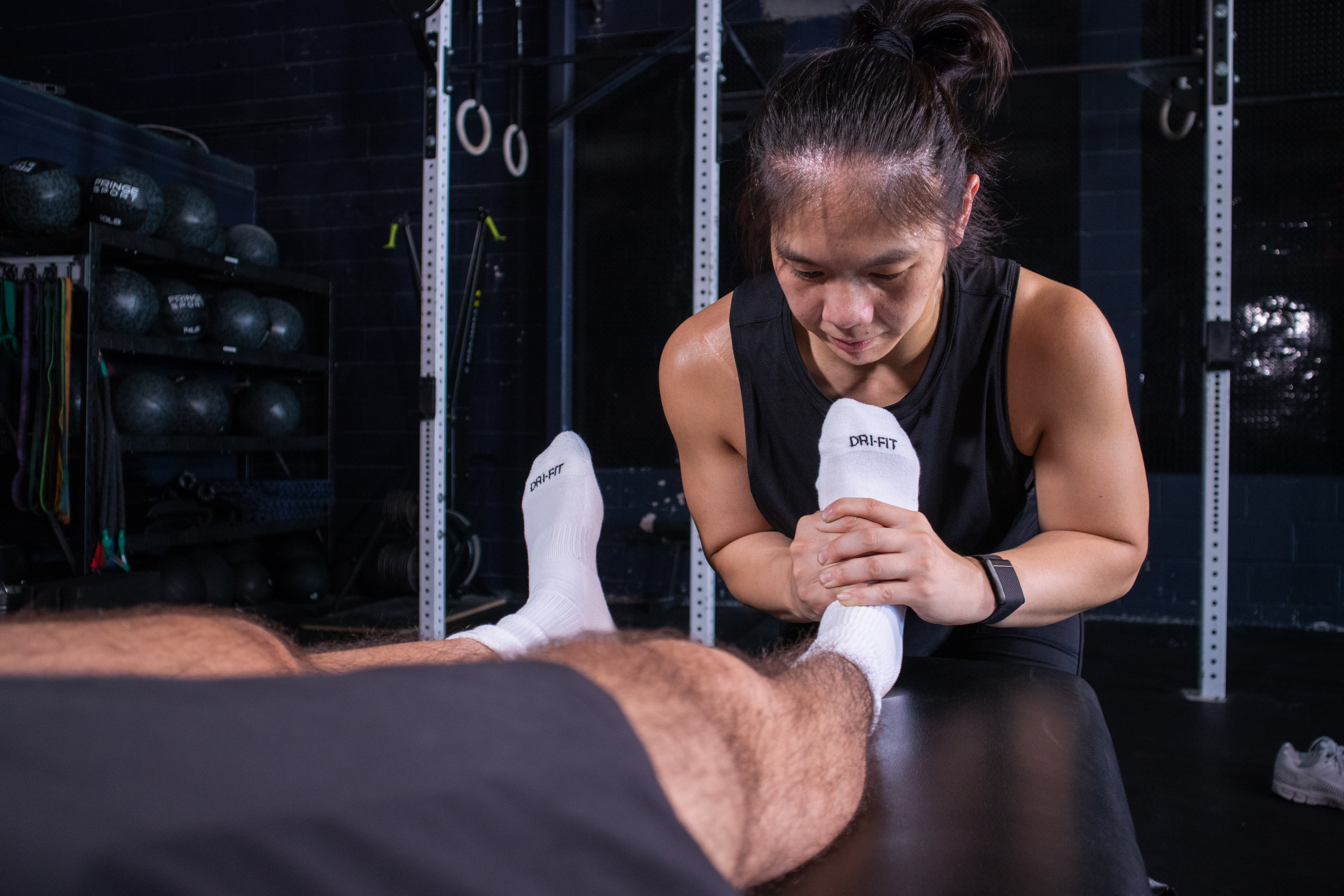 A physical therapist holds a patient's ankle beside a treatment table at PT Liftology.