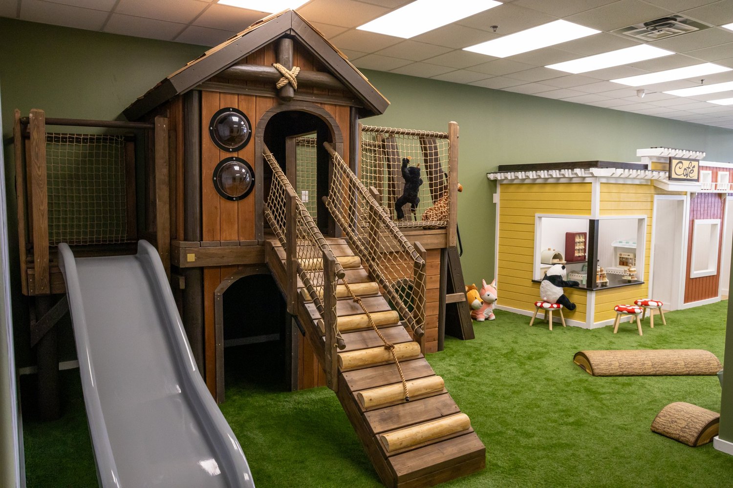 Wooden treehouse, slide, climbing ramp and pretend café inside Little Leaps Play Cafe.