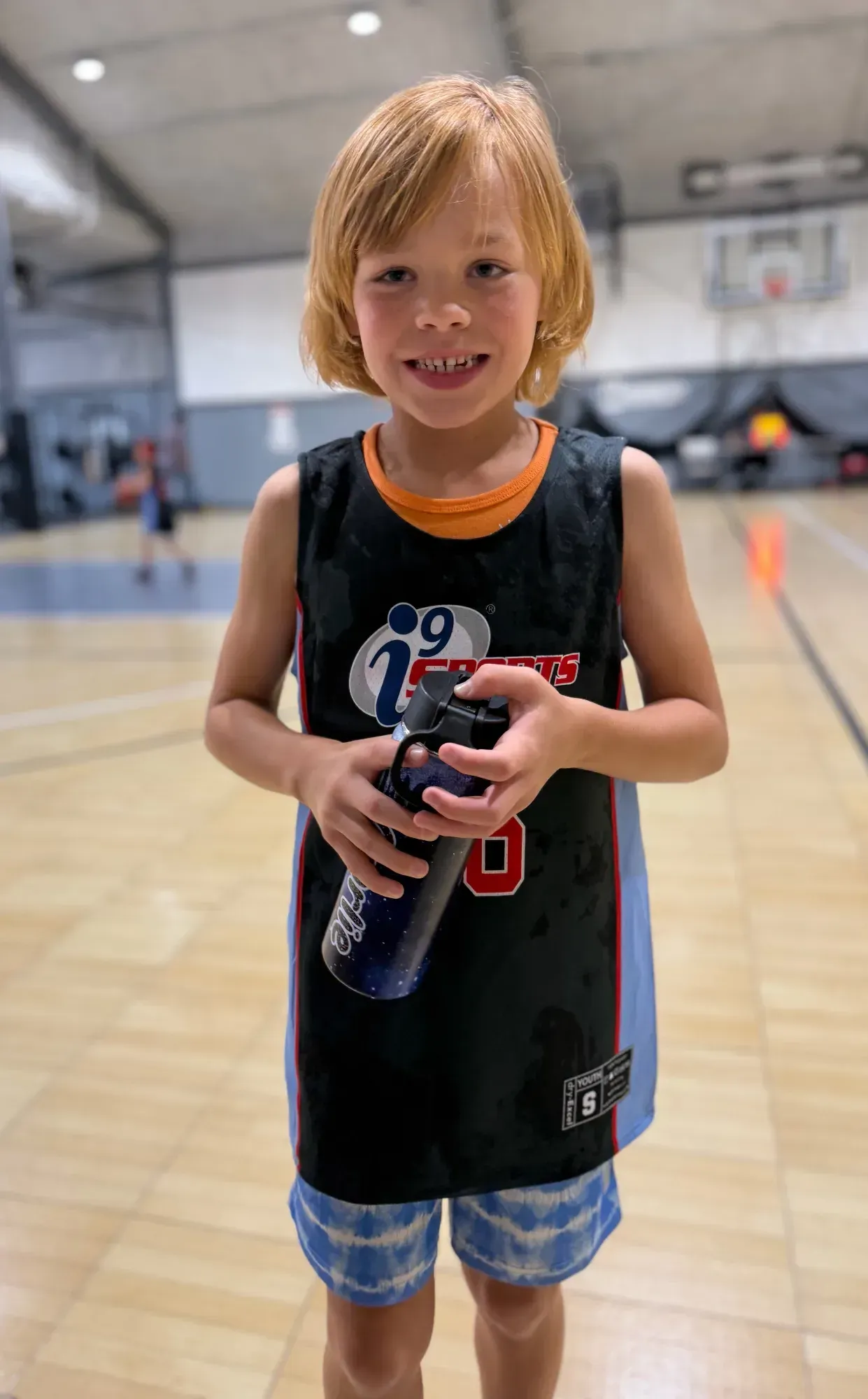 A young player with a basketball on an indoor court