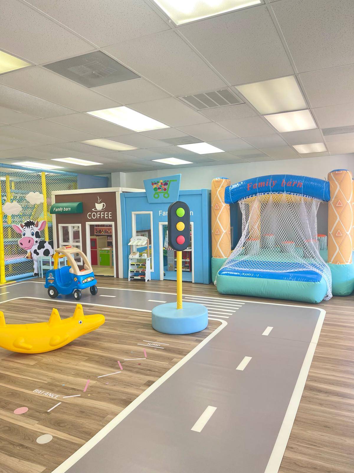 Pretend storefronts, a ride-on car and an inflatable play area inside Family Barn.