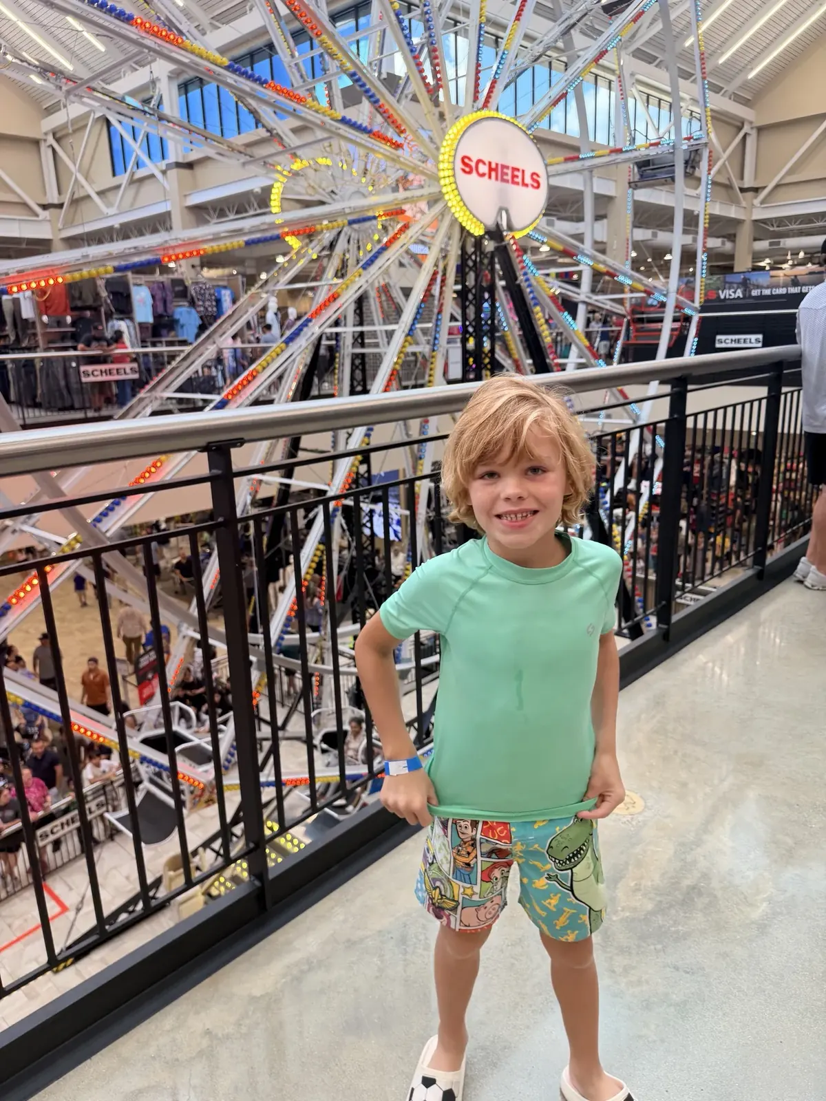 A child stands on the upper level in front of the 65-foot Ferris wheel inside Cedar Park SCHEELS