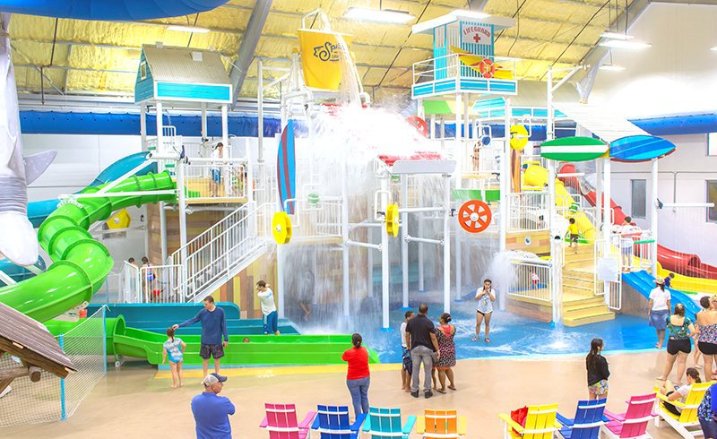 Indoor water slides and a large splash bucket above the play structure at Splash Shack.